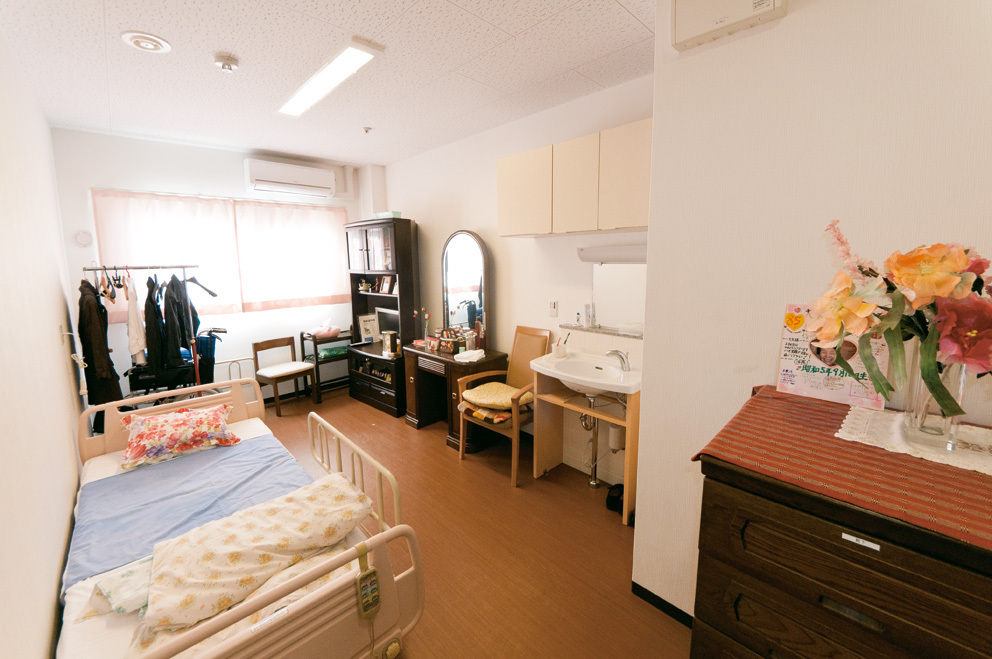介護施設の個室。ベッド、洗面台、収納、生活空間が完備されている。