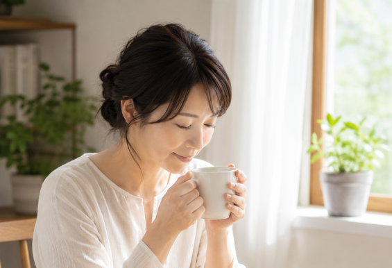 朝の窓辺で温かいミントティーを飲む女性。ストレスによるお腹の張りやゲップが気になるときのセルフケア