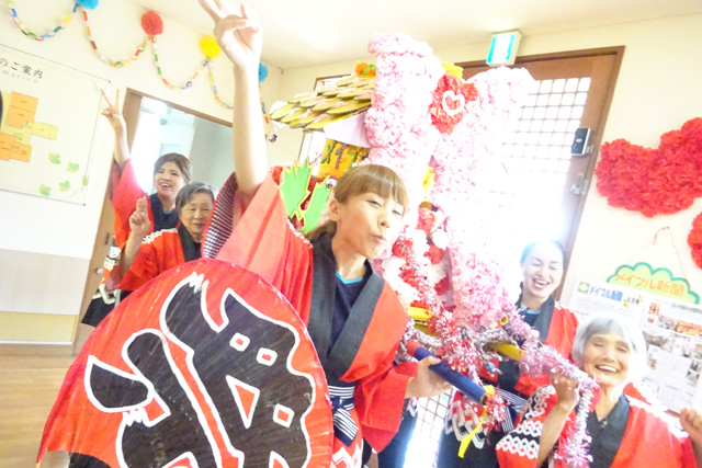 入居者と職員による祭り飾りの製作・装飾。赤と白の提灯やお花紙で施設を彩るレクリエーション活動。