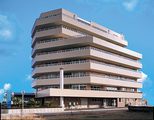 複数階の介護施設建物。モダン設計の高層建築で多くの窓と開放的なバルコニーを備えています。