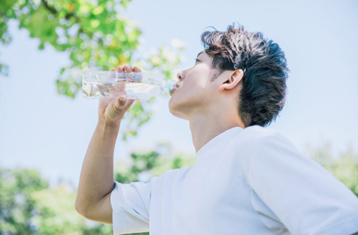 屋外でペットボトルの水を飲む男性